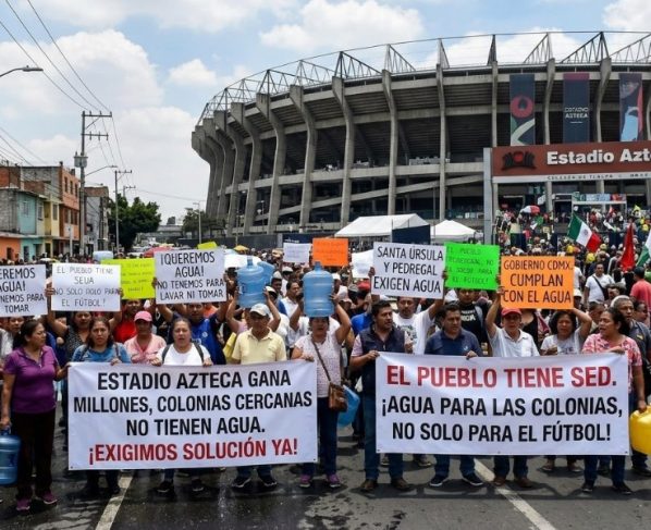 A los habitantes de la colonia Pedregal de Santa Úrsula, junto al estadio Azteca, no les han hecho justicia cuatro Mundiales de Futbol, ni los gobiernos del Partido Revolucionario Institucional, Partido de la Revolución Democrática, ni el Movimiento de Regeneración Nacional. Sus problemas de escasez de agua persisten. IMAGEN: Recreación de protestas en el Estadio Azteca con inteligencia artificial de Gemini